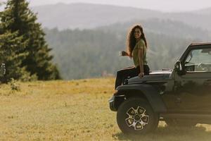 Young woman relaxing on a terrain vehicle hood at countryside photo