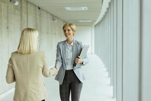 Business women handshaking in the office corridor photo