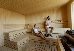 Young couple relaxing in the sauna and watching winter forest through the window photo