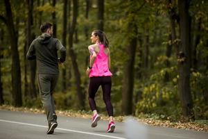Athletic couple running together on the forest trail photo
