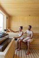 pareja joven relajándose en la sauna y viendo el bosque de invierno a través de la ventana foto