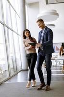 Young entrepreneur couple walking together and using digital tablet in the modern office photo