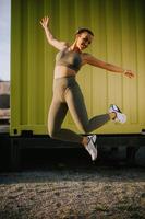 Young woman having outdoor jumping exercise photo