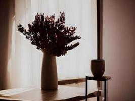 vase of flowers on a table in front of a window. Generative AI. photo