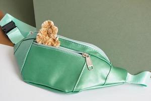 green belt bag and poisonous toadstools on a green and gray background, eco-leather from mushroom mycelium photo
