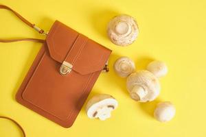 brown bag from eco leather and mushrooms on a yellow background, mycelium leather concept photo