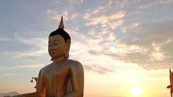 seitenansicht goldene buddha-statue gegen sonnenunterganghimmel im thailand-tempel video