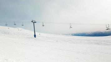 esquiador masculino esquiando cuesta abajo pase rápido vista lateral a la góndola con fondo de montañas. complejo de vacaciones de invierno de gudauri. destino de viaje de georgia. Cáucaso video