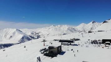 Pistas de esqui de vista aérea cinematográfica em câmera lenta na estância de esqui de gudauri com fundo de montanhas do cáucaso. video