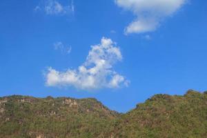 Clouds like poodle dogs float in the air in the clear sky and warm sunlight during the day and the surrounding mountains are full. photo