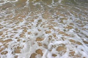 olas en la orilla de una hermosa playa tropical de arena en un día soleado foto