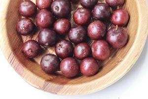 Red Fruits on wooden background. Flacourtia inermis, known commonly as lovi-lovi.  Red Fruits on white background photo