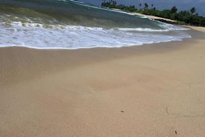 orilla del océano con playa de arena y olas que avanzan. espuma de agua con arena suave. hermosas olas en el fondo de la playa de arena. foto