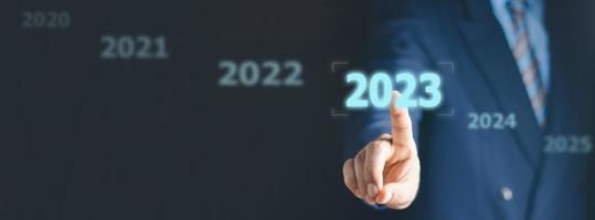 Businessman pressing 2023 start up business. Beginning of New Year 2023.Finger pressing blue start 2023 button on virtual interface on gray background with copy space for text. Concept of new year. photo
