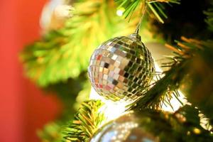 bola de cristal y bolas de navidad doradas decoradas en un pino el día de navidad con un fondo borroso de árbol de navidad. foto