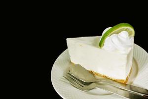 Thai style lime cream cake with teaspoon and fork on white ceramic plate and isolated on black background. photo