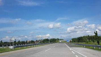 körning längs de motorväg väg eller vägtull väg infrastruktur med blå himmel och vit moln pOV skott från en kamera körning genom skön tömma väg video