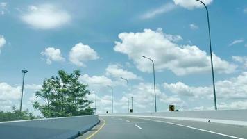 Driving along the highway road or toll road infrastructure with blue sky and white cloud POV shot from a camera driving through beautiful empty road video
