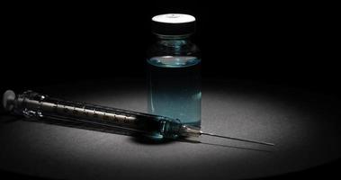 Rotating view of coronavirus vaccine and syringe on dark background video