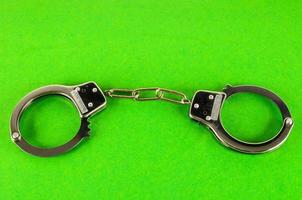 Metal handcuff on green background photo