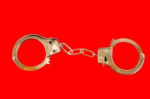 Metal handcuff on red background photo