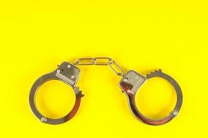 Metal handcuff on yellow background photo