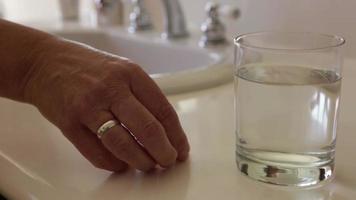 panoramique de comprimés froids effervescents tombant dans un verre d'eau près du lavabo de la salle de bain video