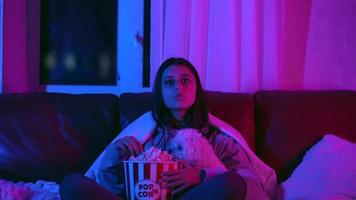 kvinna reagerar till film medan sittande på soffa med popcorn video