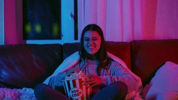 kvinna reagerar till film medan sittande på soffa med popcorn video