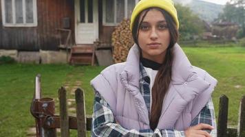 Woman outside rustic cabin looks at camera video