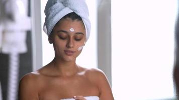 mujer aplica crema hidratante frente al espejo video