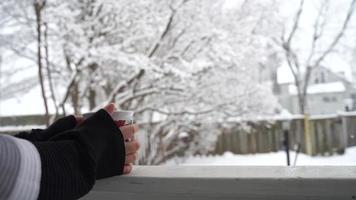 relaxando e bebendo café ou chá, as xícaras de café em um dia de neve, na varanda. conceito de relaxamento. fundo desfocado de lindo. video