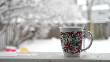 relajarse y tomar café o té, las tazas de café en un día de nieve, en el balcón. concepto de relajación. fondo borroso de hermoso. video