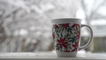 relaxando e bebendo café ou chá, as xícaras de café em um dia de neve, na varanda. conceito de relaxamento. fundo desfocado de lindo. video
