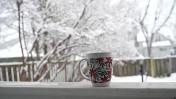 relaxando e bebendo café ou chá, as xícaras de café em um dia de neve, na varanda. conceito de relaxamento. fundo desfocado de lindo. video