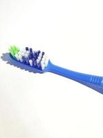 Isolated white photo of a plastic toothbrush that has been used several times. This toothbrush has a blue handle.