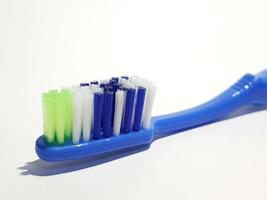 Isolated white photo of a plastic toothbrush that has been used several times. This toothbrush has a blue handle.