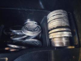 Some rupiah coins and one hundred thousand rupiah notes and some other money in a box provided on the dashboard of the car photo