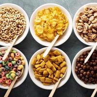 Variety of cold cereals in white bowls with spoons photo