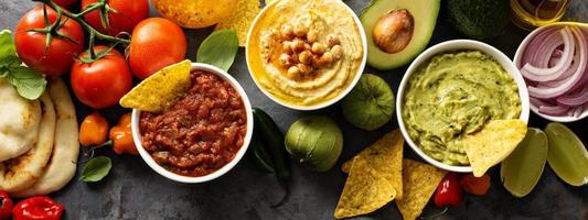 Homemade hummus, salsa and guacamole with corn chips photo