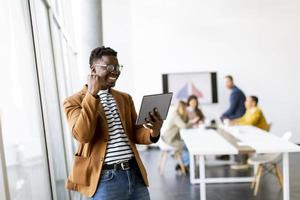 Young African American business man working with digital tablet and receiving great news in front of his coworkers at boardroom photo