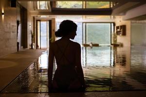 Rear view of young woman relaxing on the poolside photo