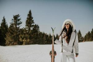 Young woman standing with skis on the ski track photo