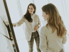 dos mujeres jóvenes discutiendo los resultados financieros en la gran pantalla de la oficina foto