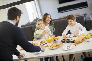 Young happy family talking while having breakfast at dining table photo