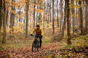 joven en bicicleta por el bosque de otoño foto