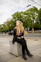 bella mujer sonriente usando teléfono móvil por el parlamento austríaco en viena, austria foto