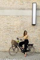 mujer con flores en la cesta de la bicicleta eléctrica foto