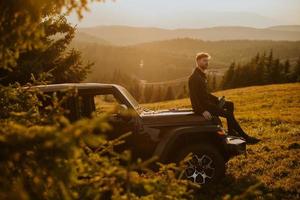 Young man relaxing on a terrain vehicle hood at countryside photo