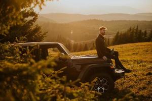 Young man relaxing on a terrain vehicle hood at countryside photo